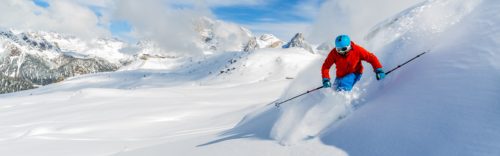 Skier skiing downhill in high mountains in fresh powder snow. Sa